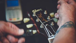 A man restringing a Les Paul electric guitar