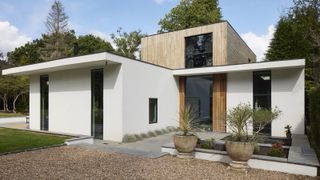 a modern two story new build home with white masonry and timber cladding