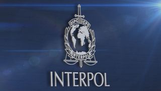 The emblem of the International Criminal Police Organization Interpol on a textured blue background.