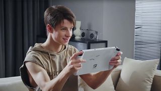 Boy playing the Tencent x Intel 3D One gaming handheld while sitting on a couch. 