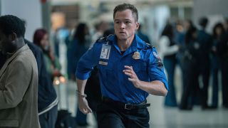 Taron Egerton running through airport dressed as TSA agent in Carry-On.