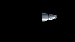 a white space capsule is seen against the blackness of space