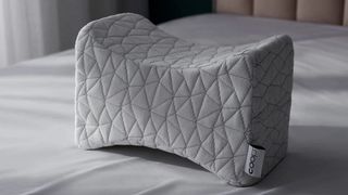 The Coop Adjustable Knee Pillow on a bed in a bedroom