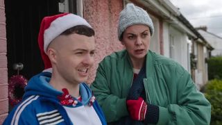 Conor MacSweeney (Alex Murphy) and mother Máiréad MacSweeney stand outside their house at Christmastime in The Young Offenders 2024 Christmas special