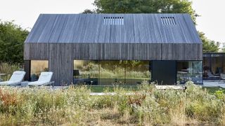 A contemporary self build home clad in timber with a dry garden with Mediterranean style planting