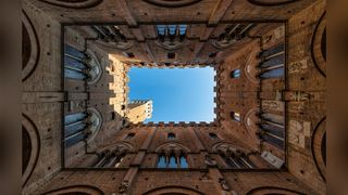 Torre del Mangia in Sienna, Italy - Photographed from the inside upwards with a 14mm wide-angle lens, showcasing symmetric and historical features 