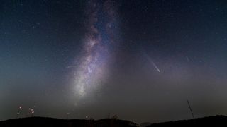 comet streaking through the starry sky. It has a long white tail. The milky way stretches through the center of the composite image.