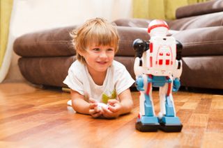 Young boy playing with a little robot.