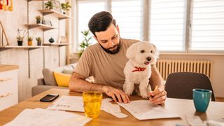 Dog sitting on owners lap while he works on finances