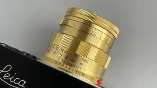 A brass Light Lens Lab 50mm f2 lens mounted on a Leica camera