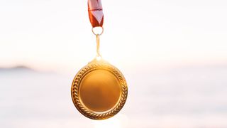 An Olympic gold medal against a backdrop of a sunset sky