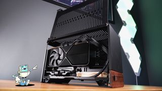 A compact gaming PC on a desk with various parts on show.