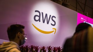 Amazon Web Services (AWS) logo pictured illuminated at Web Summit in Lisbon with attendees walking by.