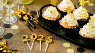 Frosted cupcakes with candles spelling out the year &#039;2025&#039;