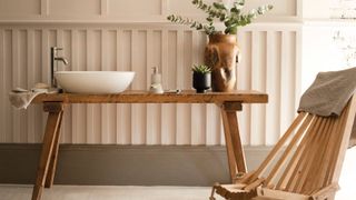 white bathroom sink on wooden table in pale pink bathroom 