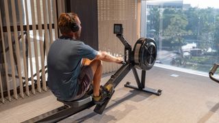 A man rowing on a rowing machine in a living room