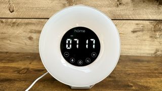 Black and white HomeLabs sunrise alarm clock on wooden surface