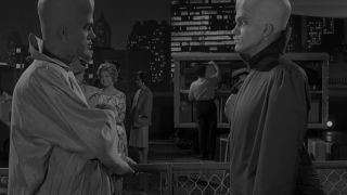 Two aliens with large heads talking in To Serve Man Twilight Zone episode