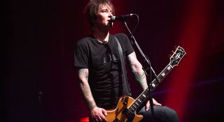 Billy Morrison plays his Gold Sparkle Gibson Les Paul Custom in front of a dark-red stage at MusiCares 2019.