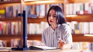 Woman scanning a book in a library using one of the best book scanners