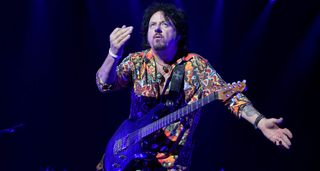 Steve Lukather onstage with his signature Ernie Ball Music Man electric guitar in blue