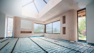 underfloor heating pipes on floor of new build home with plastered walls and large skylight