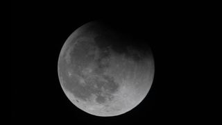 Earth&#039;s shadow partially covers the moon as viewed from the ISS