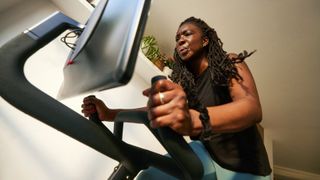 Woman pedalling hard on Peleton exercise bike