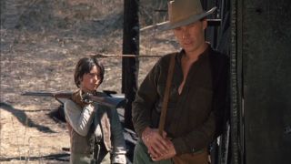 David Carradine leaning against a wall while talking with a kid in Kung Fu.