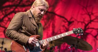 Derek Trucks takes a slide solo on his Gibson Artist Series Dickey Betts SG, with a red curtain in the background