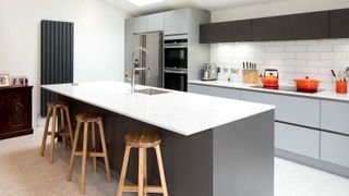 Contemporary kitchen with island unit with wooden stools and dark grey upright radiator