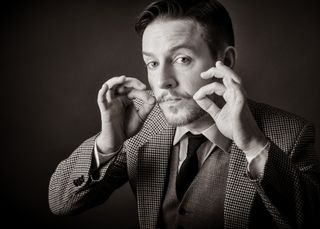 Man in tweed suit twiddling his mustache