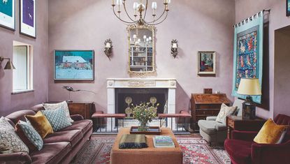 Large pink living room with fireplace, chandelier, artwork on walls, sofa, lounge chairs and ottoman