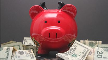 A red piggy bank with devil horns amid scattered cash.