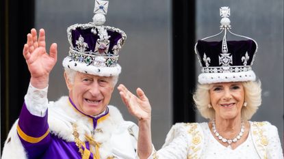 King Charles and Queen Camilla wearing crowns and robes on their coronation day and waving from the palace balcony