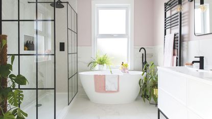 Houseplants in bathroom including monstera and calathea plant next to freestanding bath