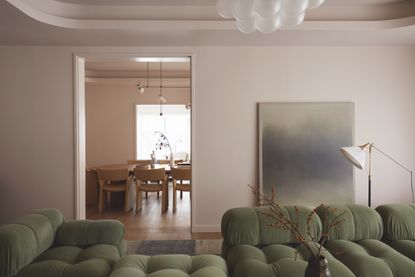 A living room with a pistachio couch, and blush pink walls