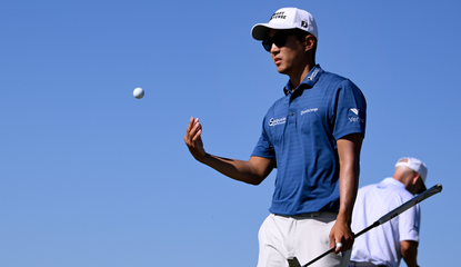 Michael Kim throws a golf ball to his caddie