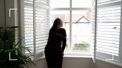 Woman with back to camera, looking out of the window, waking up in the morning after learning how to deal with sleep deprivation