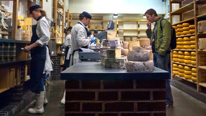 Neals Yard Dairy cheese shop interior with racks of cheeses at Borough Market London Bridge Southwark London