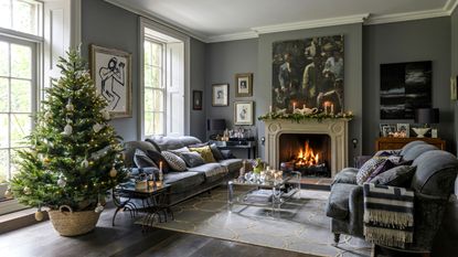 Decorated Christmas tree in woven basket in living room with fireplace