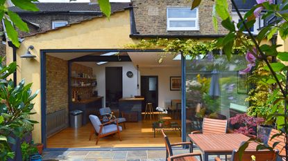 Wraparound extension seen from garden with sliding doors open to show living area with kitchen and dining area beyond