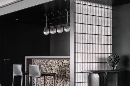 A home bar with black-painted walls, pendant lights above counter, and tall counter chairs, plus a light panel