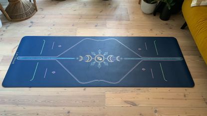 The Liforme Yoga Mat rolled out on a wooden floor in a living room setting