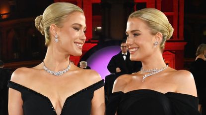 Amelia and Eliza Spencer wearing off-the-shoulder black gowns and diamond necklaces while smiling at each other