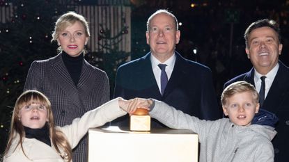 Prince Albert, Princess Charlene, Prince Jacques and Princess Gabriella wearing coats and scarves as Jacques and Gabriella press the button for a tree lighting