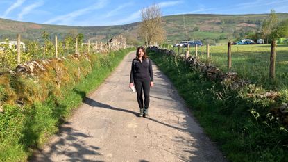 Susan Griffin wearing hiking clothes standing on a path, highlighting the benefits of an early morning walk