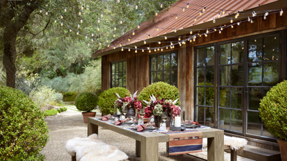 An outdoor seating with cozy throws, small plants and string lights