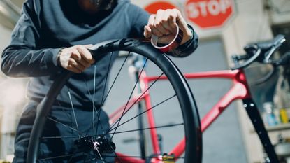 Mechanic fitting tubeless rim tape to a tubeless-ready wheel