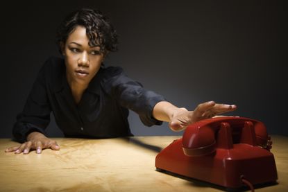 Businesswoman reaching to answer a red telephone